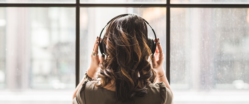 woman looking at the window listening with her headphones